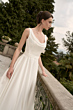 Abito da sposa elegante Varley Romantica Collection, donna su balcone con sfondo verde.