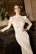 Abito da sposa in pizzo bianco della collezione Romantica, GEMMA, indossato in un elegante ambiente interno.