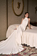 Abito da sposa elegante Malika della Romantica Collection su letto in camera classica.