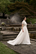 Abito da sposa Beatrice in pizzo e chiffon, collezione Romantica, in giardino con fontana sullo sfondo.