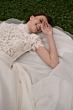Abito da sposa in pizzo BEATRICE, collezione Romantica, indossato da modella sorridente su prato verde.