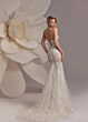 Abito da sposa SHEYNISS EVA LENDEL, schiena scoperta, dettagli floreali, sfondo con fiore gigante.